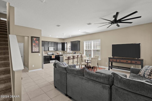 living room featuring light tile patterned flooring, a textured ceiling, and ceiling fan