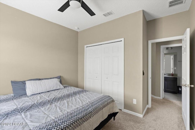 bedroom featuring a closet, a textured ceiling, light colored carpet, and ceiling fan