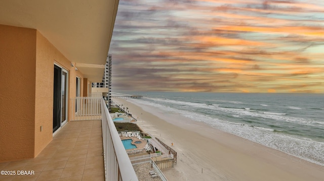 balcony at dusk with a beach view and a water view