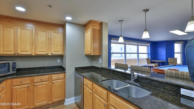 kitchen featuring a sink, pendant lighting, appliances with stainless steel finishes, recessed lighting, and dark stone counters