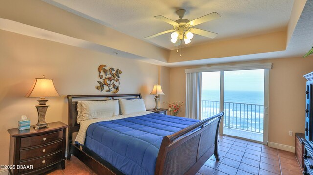 tiled bedroom featuring a tray ceiling, baseboards, access to exterior, and a textured ceiling