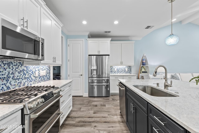 kitchen featuring hanging light fixtures, sink, white cabinets, and appliances with stainless steel finishes