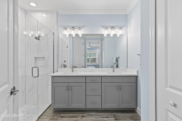 bathroom featuring vanity, a shower with shower door, ornamental molding, and wood-type flooring