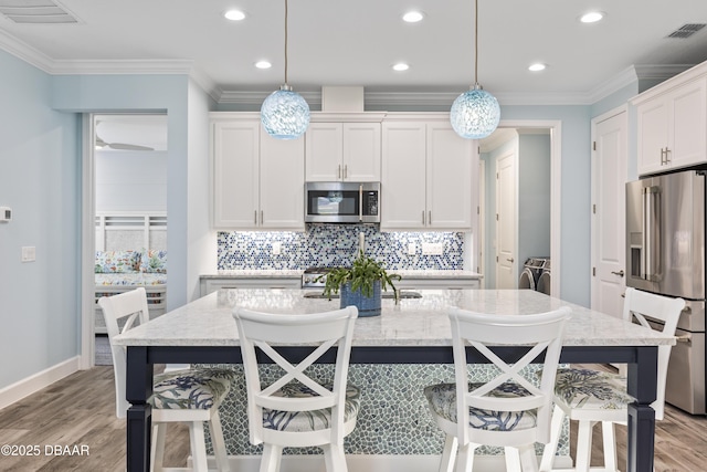 kitchen with stainless steel appliances, hanging light fixtures, separate washer and dryer, and white cabinets