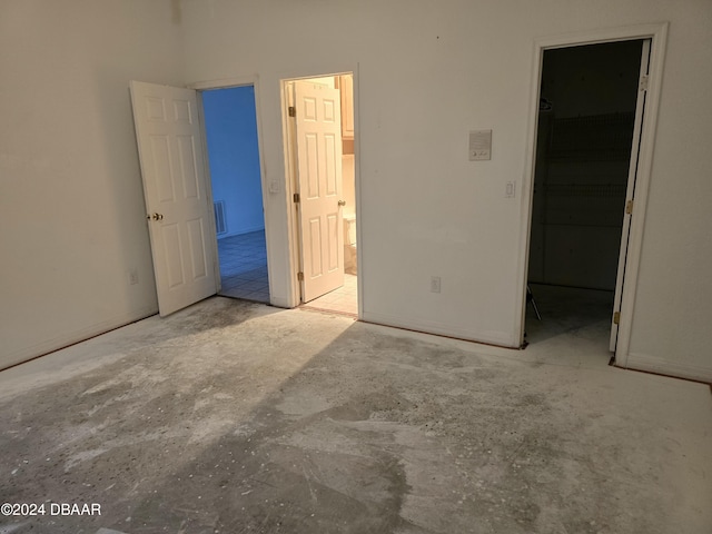 unfurnished bedroom with ensuite bathroom, a walk in closet, and a closet