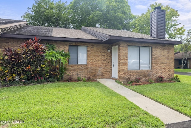 1518 Franklin Cir, Holly Hill, FL 32117 - single story home with a front yard, brick siding, a chimney, and roof with shingles