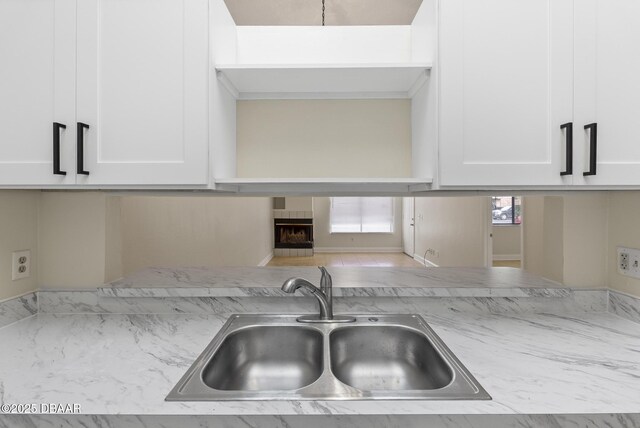 1518 Franklin Cir, Holly Hill, FL 32117 - kitchen featuring a sink, white cabinetry, light stone countertops, and a fireplace