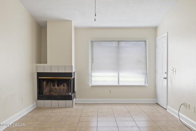 1518 Franklin Cir, Holly Hill, FL 32117 - unfurnished living room featuring a tiled fireplace, baseboards, tile patterned flooring, and a textured ceiling