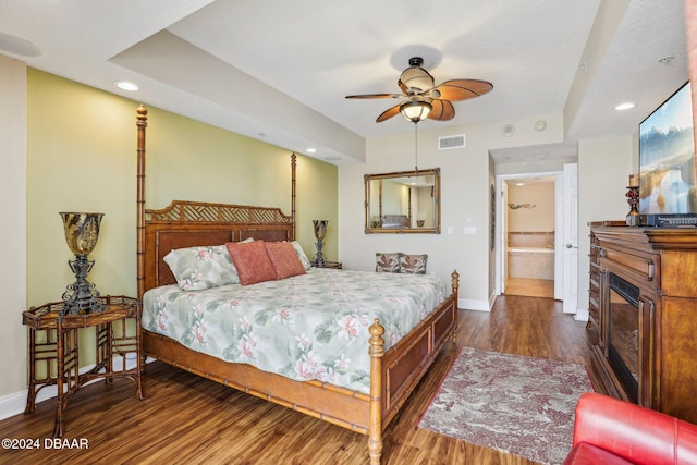 bedroom featuring ceiling fan, dark wood-type flooring, and ensuite bath