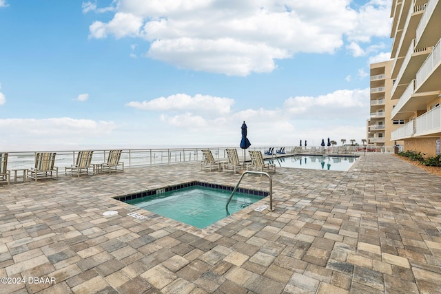 view of swimming pool featuring a water view, a hot tub, and a patio area