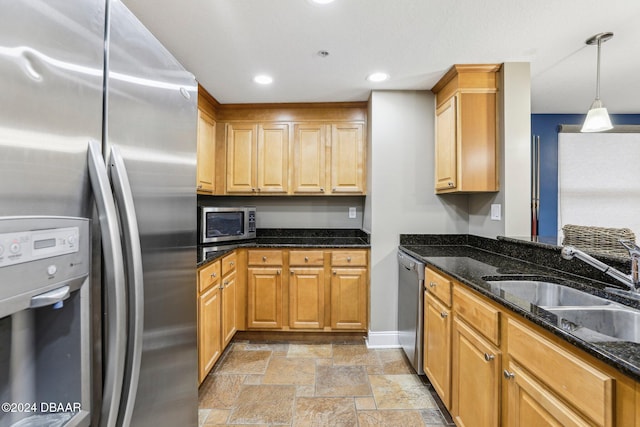 kitchen featuring decorative light fixtures, sink, stainless steel appliances, and dark stone counters