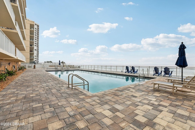 view of pool with a patio area and a water view