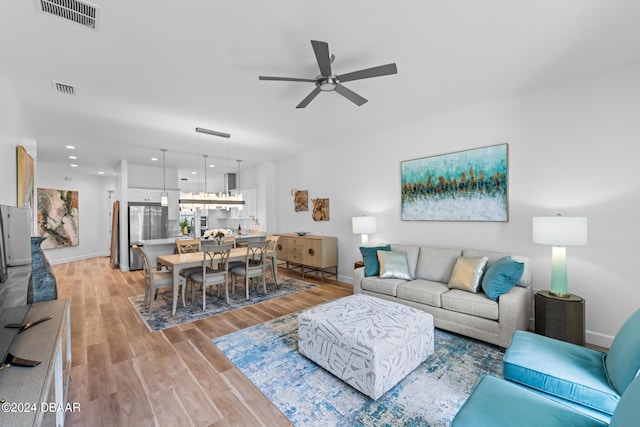 living room with light hardwood / wood-style flooring and ceiling fan