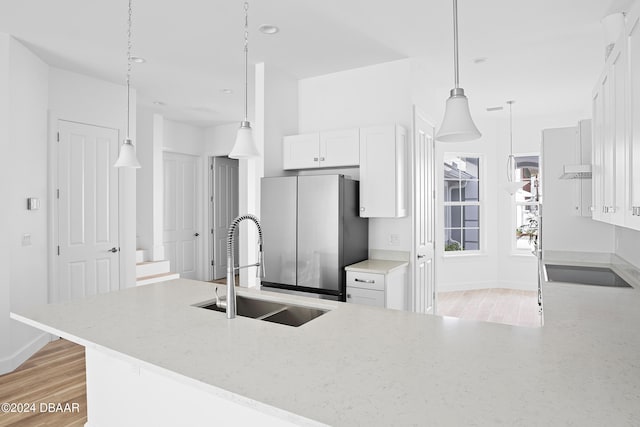 kitchen featuring light hardwood / wood-style floors, stainless steel refrigerator, white cabinetry, and sink