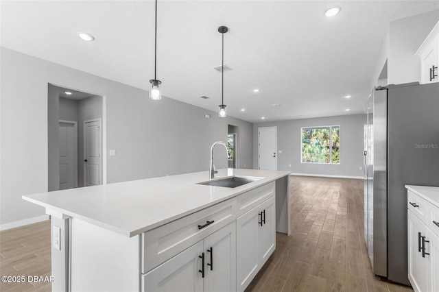 23 Weymouth Ln, Palm Coast, FL 32164 - kitchen featuring freestanding refrigerator, light wood-type flooring, light countertops, a center island with sink, and recessed lighting