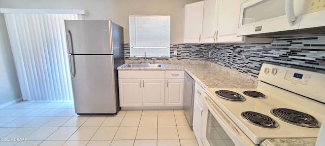 kitchen with appliances with stainless steel finishes, light countertops, white cabinets, a sink, and light tile patterned flooring