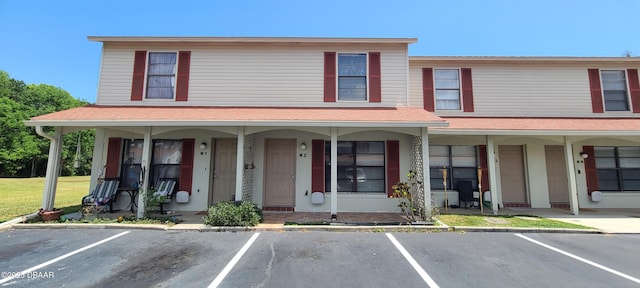 view of property with a porch and uncovered parking