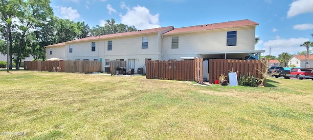 rear view of house with a lawn and fence