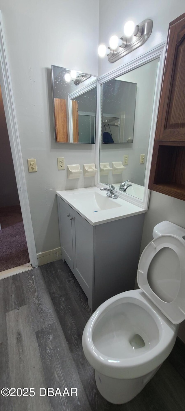 bathroom with baseboards, wood finished floors, toilet, and vanity