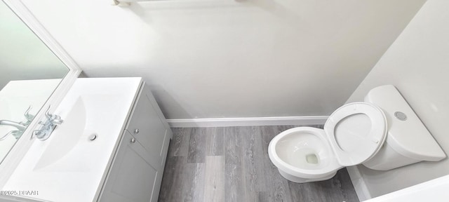 bathroom with baseboards, wood finished floors, toilet, and vanity