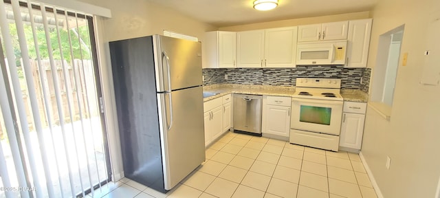 kitchen featuring light tile patterned flooring, white cabinets, appliances with stainless steel finishes, and decorative backsplash