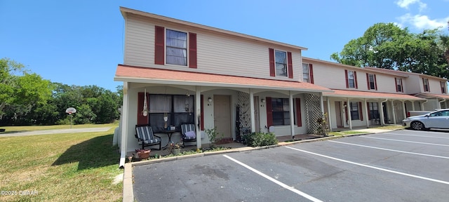 multi unit property with uncovered parking, a front lawn, and covered porch