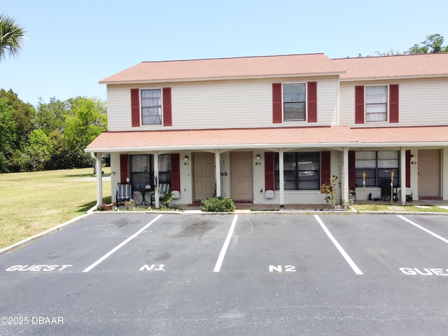 multi unit property with a porch, uncovered parking, and a front lawn