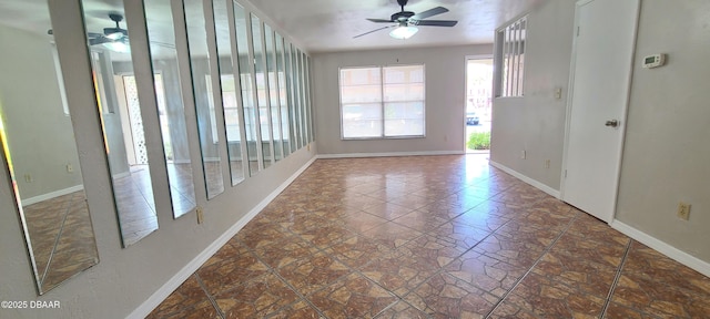 empty room with ceiling fan and baseboards