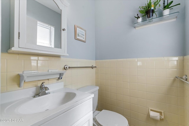 half bath featuring toilet, a wainscoted wall, tile walls, and vanity