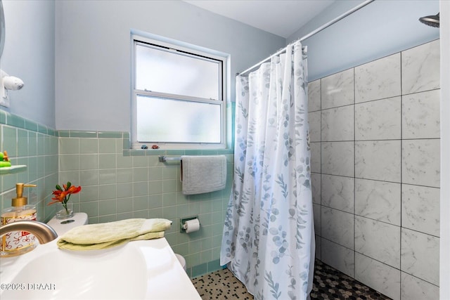 full bath with tiled shower, a sink, and tile walls