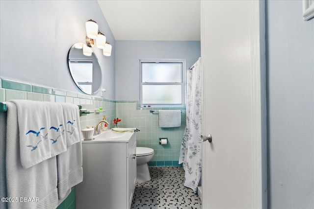 full bath featuring a wainscoted wall, tile walls, toilet, vanity, and tile patterned flooring