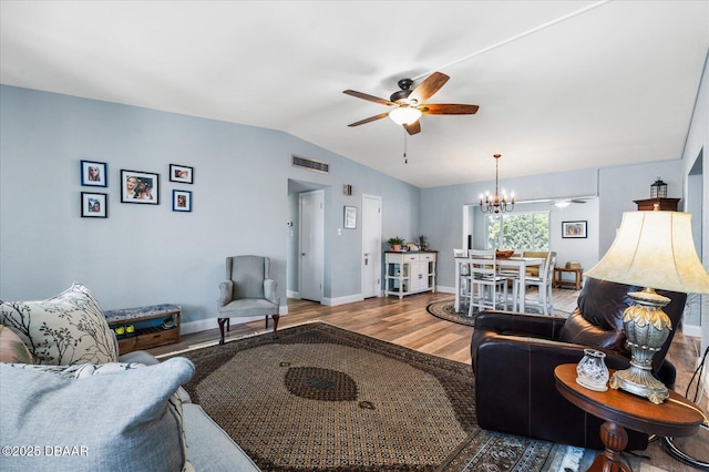 living room featuring baseboards, visible vents, wood finished floors, vaulted ceiling, and ceiling fan with notable chandelier