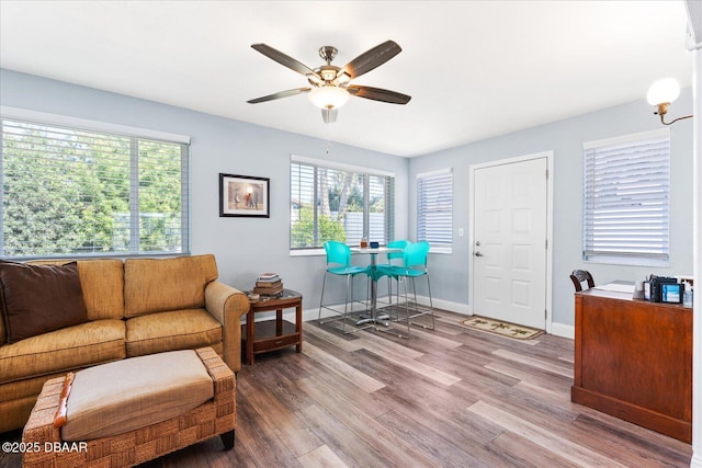 living area featuring wood finished floors, a ceiling fan, and baseboards