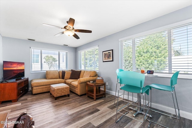 living area featuring a ceiling fan, baseboards, visible vents, and wood finished floors