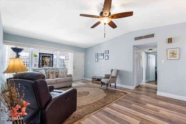 living area with vaulted ceiling, wood finished floors, visible vents, and baseboards