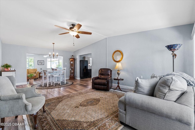 living room featuring lofted ceiling, ceiling fan with notable chandelier, wood finished floors, and baseboards