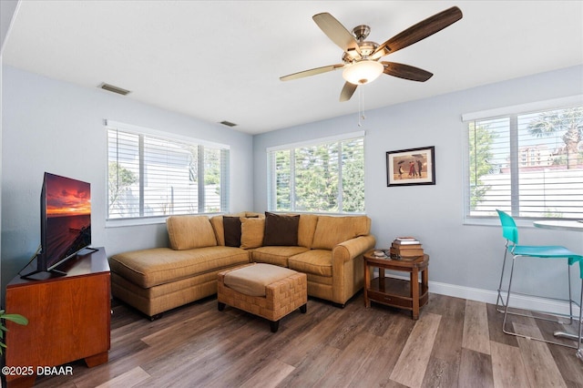 living area featuring a ceiling fan, wood finished floors, visible vents, and baseboards