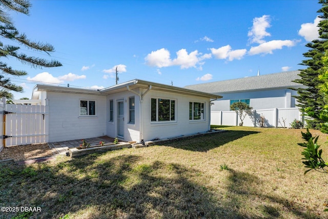 back of house with fence and a lawn