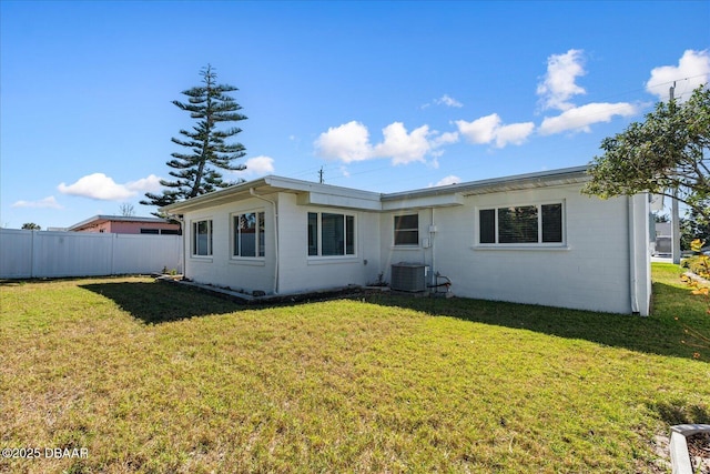 rear view of property featuring fence, cooling unit, and a yard