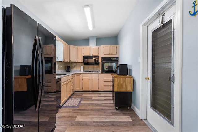 kitchen featuring light countertops, backsplash, light wood-style floors, light brown cabinets, and black appliances