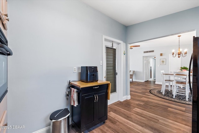 hallway with a notable chandelier, dark wood finished floors, visible vents, and baseboards