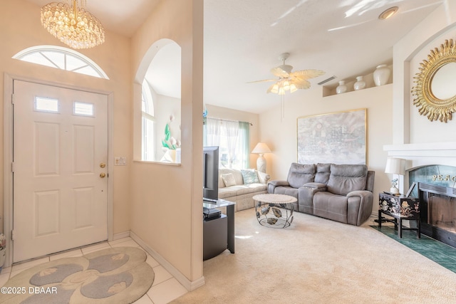 entryway with light carpet, ceiling fan with notable chandelier, and a fireplace