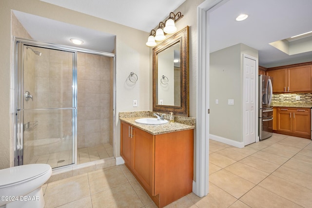 bathroom featuring toilet, tile patterned floors, backsplash, and a shower with shower door