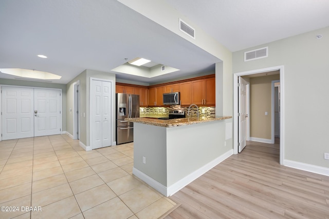 2 Oceans W Blvd Unit 707, Daytona Beach, FL 32118 - kitchen with stainless steel appliances, decorative backsplash, a peninsula, a sink, and baseboards