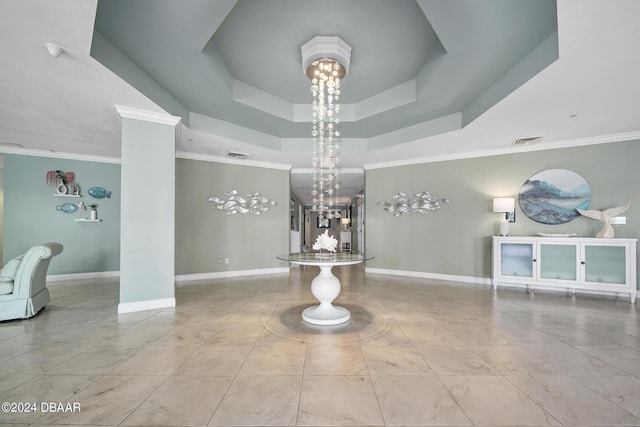 interior space with ornamental molding, a raised ceiling, and ornate columns