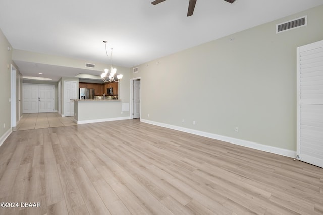 unfurnished living room featuring ceiling fan with notable chandelier and light wood-type flooring