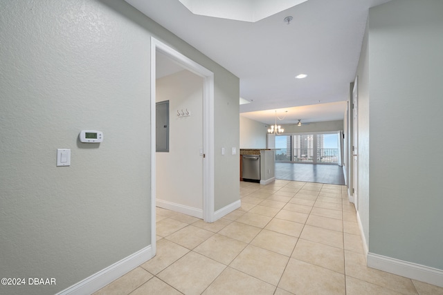 corridor with a notable chandelier, light tile patterned floors, and electric panel