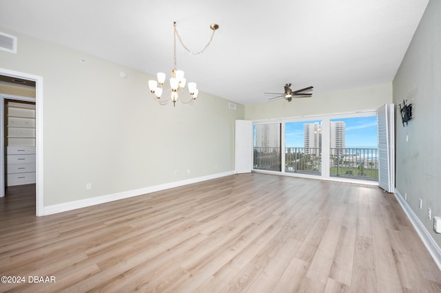 unfurnished living room featuring ceiling fan with notable chandelier and light hardwood / wood-style flooring