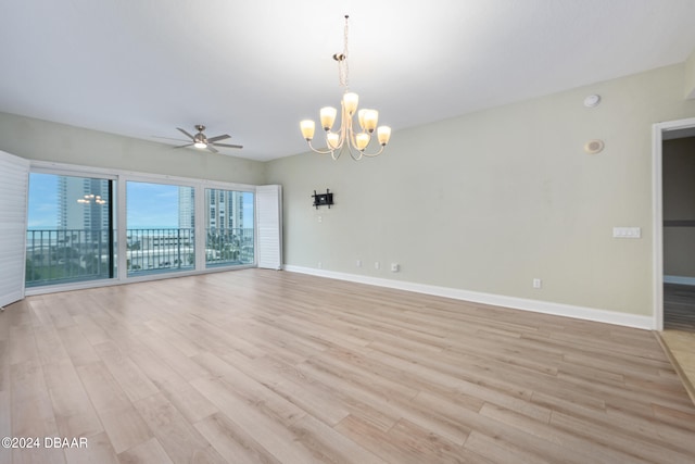 spare room featuring ceiling fan with notable chandelier and light hardwood / wood-style flooring