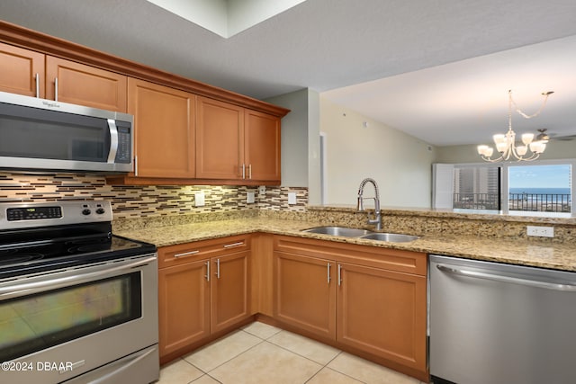 kitchen with light stone counters, sink, backsplash, and appliances with stainless steel finishes